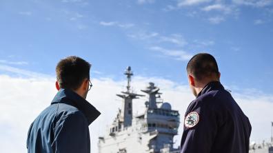 Deux cybercombattants de la Marine nationale devant un porte-hélicoptères amphibie (PHA)