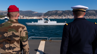 Un soldat et un marin regardent un navire quitter le port de Toulon.