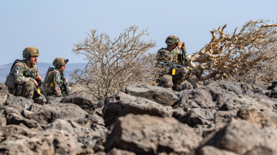 Trois marsouins du groupement tactique embarqué progressent dans le milieu désertique rocailleux.